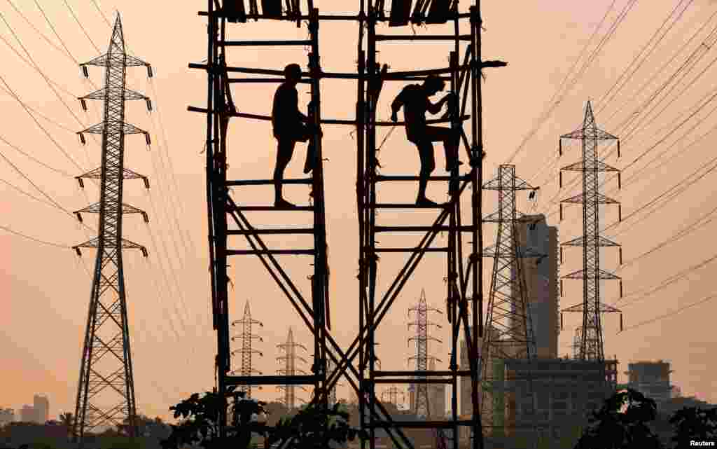 Laborers work next to electricity pylons in Mumbai, India.