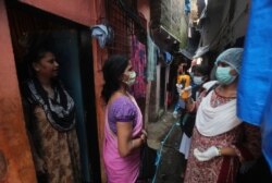 FILE - A health worker screens people for symptoms of COVID-19 in Dharavi, one of Asia's biggest slums, in Mumbai, India, Sept. 4, 2020.