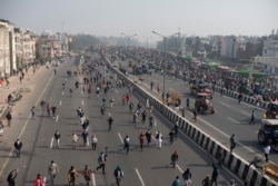 FILE - Protesting farmers run during their march to the capital breaking police barricades during India's Republic Day celebrations in New Delhi, India, Jan. 26, 2021.