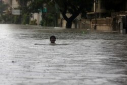 FILE - A man wades through the flooded street during monsoon rain, in Karachi, Pakistan, Aug. 27, 2020.