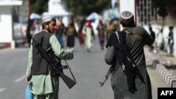Taliban fighters walk at the main entrance gate of Kabul airport in Kabul, Aug. 28, 2021. 
