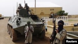 Fighters from the Al Qaeda-linked Islamist group MUJWA, who are traveling with a convoy including Burkina Faso Foreign Minister Djibril Bassole, stand guard in Gao, northern Mali, August 7, 2012. 