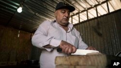 Bahaa Fransaw, cuts kebab meat, for his food stall, in Hamdaniya, Iraq, March 29, 2017. 