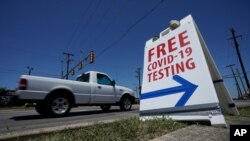 FILE - A pick-up truck passes a sign for free COVID-19 testing, in San Antonio, Texas, Aug. 14, 2020.