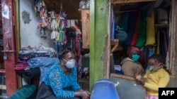 A woman and her child wear face masks as preventive measure against the COVID-19, in her shop inLilongwe City market in Lilongwe, Malawi, May 18, 2020.