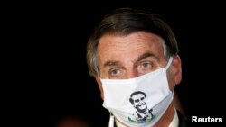 Brazil's President Jair Bolsonaro speaks with journalists while wearing a protective face mask as he arrives at Alvorada Palace, amid the coronavirus disease outbreak, in Brasilia, May 22, 2020. 