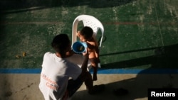 Un migrante venezolano alimenta a su hijo dentro de un coliseo donde se ha instalado un campamento temporal, luego de huir de operaciones militares en su país, según la agencia colombiana de migración, en Arauquita, Colombia el 27 de marzo de 2021.