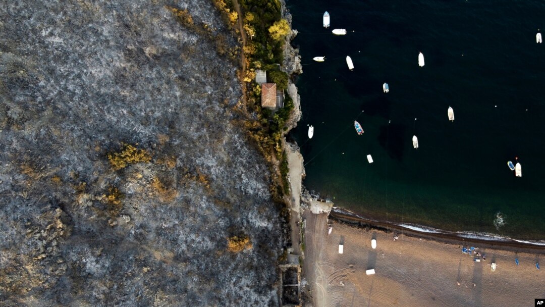 A burnt mountain over a beach in Agia Anna village on Evia island, about 148 kilometers (92 miles) north of Athens, Greece, Aug. 10, 2021.