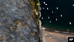 A burnt mountain over a beach in Agia Anna village on Evia island, about 148 kilometers (92 miles) north of Athens, Greece, Aug. 10, 2021.