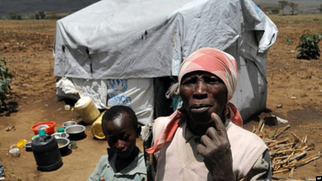 A resident of Vumilia Eldoret Camp with family. Many residents have lived for three years in tents intended to last for six months.
