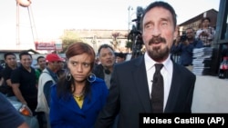 Le fondateur d'une société de logiciels, John McAfee, à droite, accompagné de sa petite amie (qui deviendra son épouse), après une conférence de presse devant la Cour suprême à Guatemala City, au Guatemala, le mardi 4 décembre 2012.