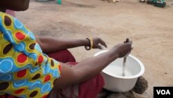 A mother cooking porridge for her children in Dowa district, Malawi. In some families the new school home feeding programs is helping suppliment family food. (Lameck Masina/VOA)