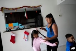 FILE - Diomaris Barboza braids her daughter's hair in the home the family moved into in October 2023, five years after fleeing Venezuela for Colombia, in Lehigh Acres, Fla., Dec. 27, 2023.