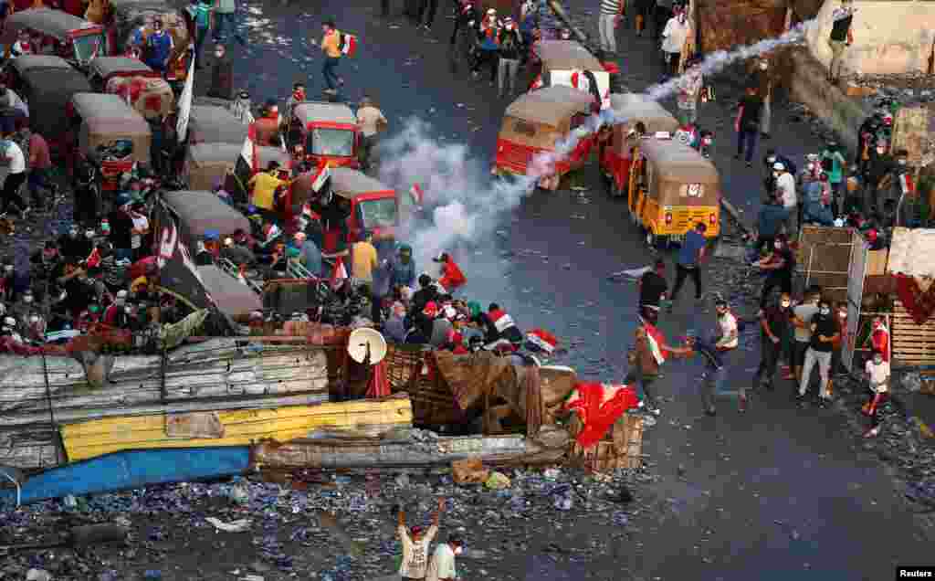 Demonstrators are seen running, after Iraqi security forces fired tear gas during a protest over corruption, lack of jobs, and poor services, in Baghdad.