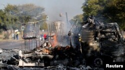 Un habitant passe devant un camion incendié près de la route où les manifestants sont passés à Atteridgeville, à l'ouest de Pretoria, Afrique du Sud, le 21 juin 2016.