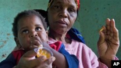 A child with HIV is given medication by a care-giver in Durban, South Africa