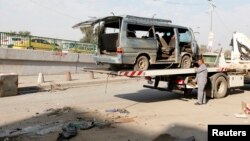 A worker prepares to remove the wreckage of a vehicle at one of the sites of car bomb attacks in Baghdad, Iraq, Dec. 8, 2013.