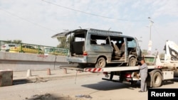 Seorang pekerja bersiap memindahkan rongsokan kendaraan di tempat kejadian serangan bom di Baghdad, Iraq, 8 Desember 2013.