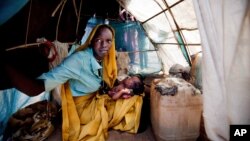 Ashia Saleh, from Barkatil village, holds her baby inside a make shift tent at the Kalma refugee camp for internally displaced people, south of the Darfur town of Nyala, Sudan, March 9, 2014. (Credit: UNAMID)