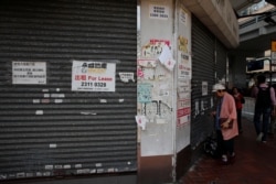 A woman stands in front of a closed shop available for lease in Hong Kong, China, Oct. 29, 2019.