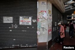 A woman stands in front of a closed shop available for lease in Hong Kong, China, Oct. 29, 2019.