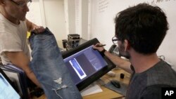 Bart Sights, head of the Eureka Lab, left, and Aykut Aygun, manager of technical innovation, give a demonstration on designing jeans at Levi's innovation lab in San Francisco, Feb. 9, 2018.