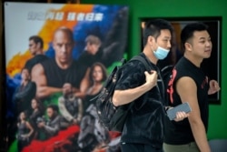 人們走過北京街頭張貼的美國大片“激情與速度9”的廣告。 （2021年5月26日）