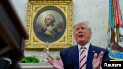 U.S. President Donald Trump answers questions from reporters sitting in front of a portrait of former U.S. President George Washington in the Oval Office of the White House in Washington, Aug. 20, 2019.