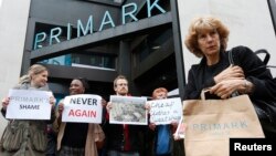 A shopper passes demonstrators outside clothing retailer Primark in central London, April 27, 2013. 