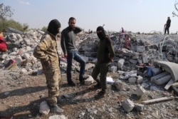 FILE - People look at a destroyed houses near the village of Barisha, in Idlib province, Syria, Oct. 27, 2019, after an operation by the U.S. military that targeted Abu Bakr al-Baghdadi.