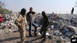People look at a destroyed houses near the village of Barisha, in Idlib province, Syria, Oct. 27, 2019, after an operation by the U.S. military which targeted Abu Bakr al-Baghdadi. 