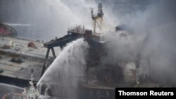 A Sri Lankan navy boat sprays water on the New Diamond, a very large crude carrier that was carrying about 2 million barrels of oil, after a fire broke out off the east coast of Sri Lanka, September 8, 2020. 