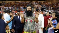 FILE - In this Oct. 5, 2016 file photo, Indian spiritual guru who calls himself Dr. Saint Gurmeet Singh Ram Rahim Insan, center, greets followers as he arrives for a press conference ahead of the release of his new movie "MSG: The Warrior Lion Heart," in 