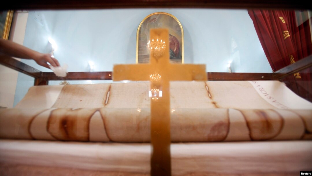 Seorang laki-laki menyentuh salinan asli Shroud of Turin dalam pameran di Beirut tahun 2010. Kain ini diyakini sebagai pakaian yang dikenakan Jesus ketika dimakamkan. 