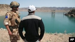 FILE - A British soldier stands with an Afghan interpreter with part of the Kajaki power dam in the background in Kajaki, Helmand province, south of Kabul, Afghanistan, April 16, 2008.