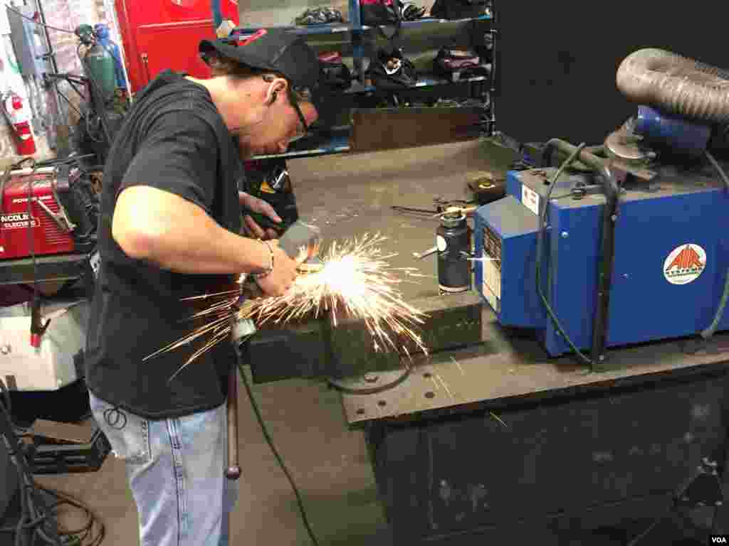 American College of the Building Arts student Alex Fisher grinds an iron door handle, Charleston, S.C., Sept. 17, 2019. (J. Taboh/VOA News)