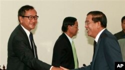 PM Kamboja Hun Sen (kanan) berjabat tangan dengan pemimpin oposisi Sam Rainsy sebelum pembicaraan hari kedua terkait upaya penyelesaian krisis politik negara itu di Phnom Penh (17/9).