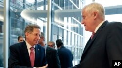 Hans-Georg Maassen, left, head of the German Federal Office for the Protection of the Constitution, and German Interior Minister Horst Seehofer, right, shake hands as they arrive for a hearing at the home affairs committee of the German federal parliament, Bundestag, in Berlin, Germany, Wednesday, Sept. 12, 2018.