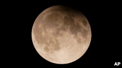 FILE - A supermoon with a partial lunar eclipse rises over Lake Michigan in Chicago, Sept. 17, 2024.