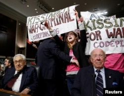 ARCHIVO: Manifestantes de Code Pink rodean a los exsecretarios de Estado de Estados Unidos, Henry Kissinger (izq) y George Shultz, antes del comienzo del una audiencia de la Comisión de Servicios Armados del Senado en el Capitolio en Washington el 29 de enero de 2015.