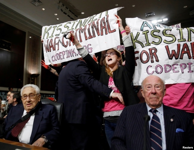 ARCHIVO: Manifestantes de Code Pink rodean a los exsecretarios de Estado de Estados Unidos, Henry Kissinger (izq) y George Shultz, antes del comienzo del una audiencia de la Comisión de Servicios Armados del Senado en el Capitolio en Washington el 29 de enero de 2015.