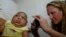 Pediatrician Alexia Harrist from the United States' Centers for Disease Control and Prevention (CDC) takes a picture of 3-month-old Shayde Henrique who was born with microcephaly, after examining him in Joao Pessoa, Brazil, Feb. 23, 2016. 