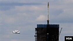 Enterprise yang digendong Boeing 747 terbang dekat One World Trade Center yang sedang dibangun di Ground Zero, NYC , Jumat (27/4).