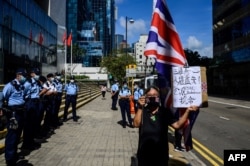 Alexandra Wong (kanan), aktivis yang dikenal sebagai Nenek Wong, memegang bendera Inggris Union Jack di luar Pengadilan Distrik di Hong Kong, 28 Mei 2021, saat sembilan aktivis pro-demokrasi menunggu hukuman mereka atas tuduhan pertemuan tanpa ijin.