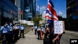 Alexandra Wong (R), an activist known as Grandma Wong, holds a British Union Jack flag outside the District Court in Hong Kong on May 28, 2021, as nine pro-democracy activists await their sentencing for charges of unauthorized assembly.