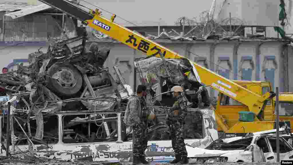 Les forces de sécurité afghanes à côté de véhicules calcinés après l&#39;explosion à Kaboul, 19 avril 2016.