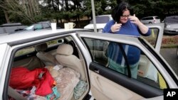 Lisa Davis shows how she has her car set up to live in the church parking lot she shares with two-dozen or so other vehicles and their occupants, homeless single women, in Kirkland, Wash., March 5, 2018.