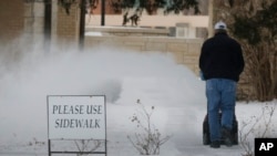 Un trabajador limpia de nieve una acera en Lawrence, Kansas.