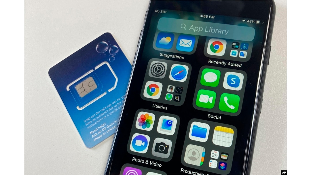 FILE - A SIM card is shown next to a cellphone in this photo taken on Tuesday, June 11, 2024 in London. Physical SIM cards are going away, replaced by eSIMs which make switching cell carriers easier. AP Photo/Kelvin Chan)