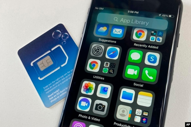 FILE - A SIM card is shown next to a cellphone in this photo taken on Tuesday, June 11, 2024 in London. Physical SIM cards are going away, replaced by eSIMs which make switching cell carriers easier. AP Photo/Kelvin Chan)